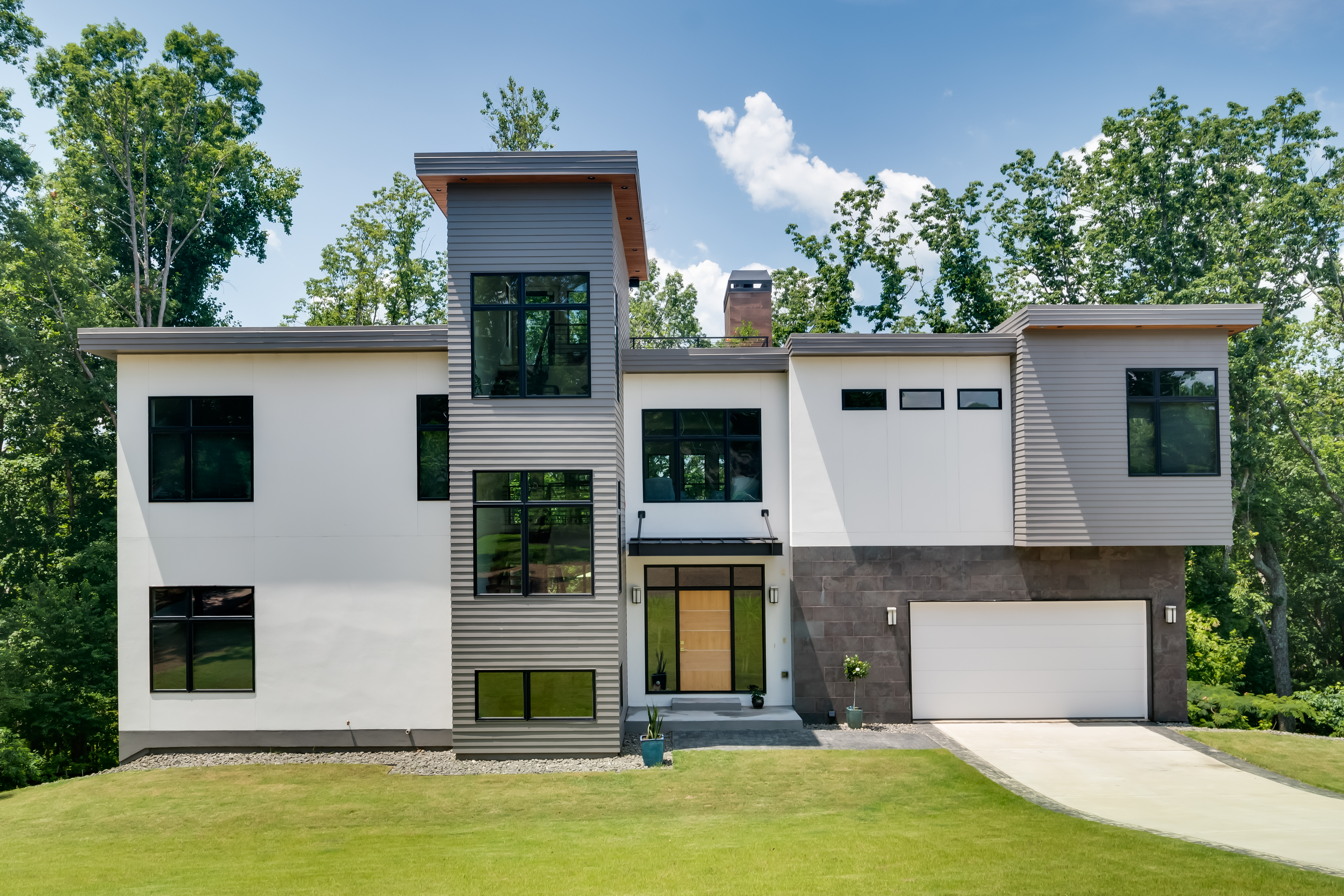 A Georgia modern home with white and grey cladding, various window sizes and trees in the background