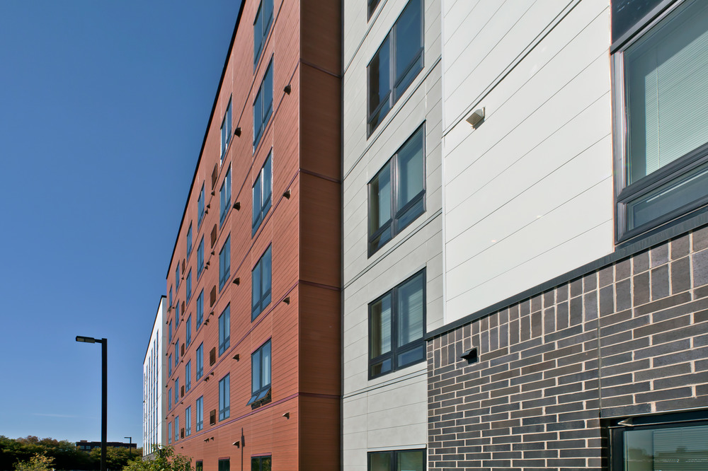 The side of an apartment complex cladded in separate sections using Nichiha Concrete Series, Designer Series, Wood Series, IndustrialBlock and Illumination. 