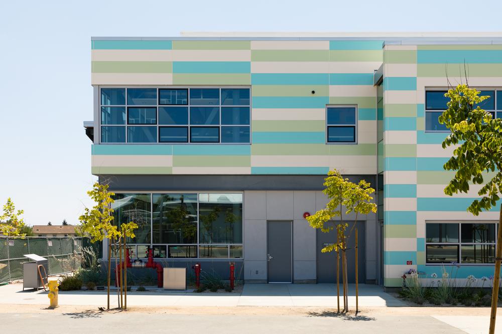 Tennyson High School with custom-colored Nichiha fiber cement cladding in green, white and blue.