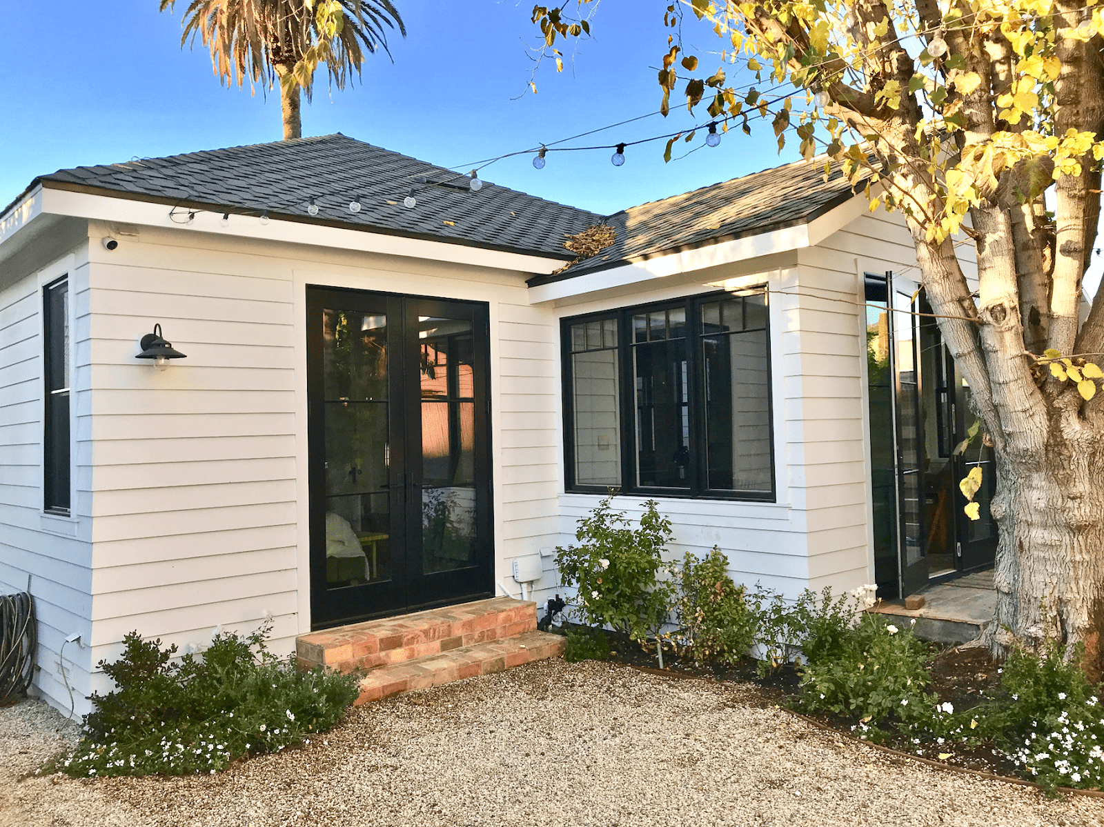 The back door of the home taken at an angle, showing the white Nichiha siding and black trimmed doors and windows