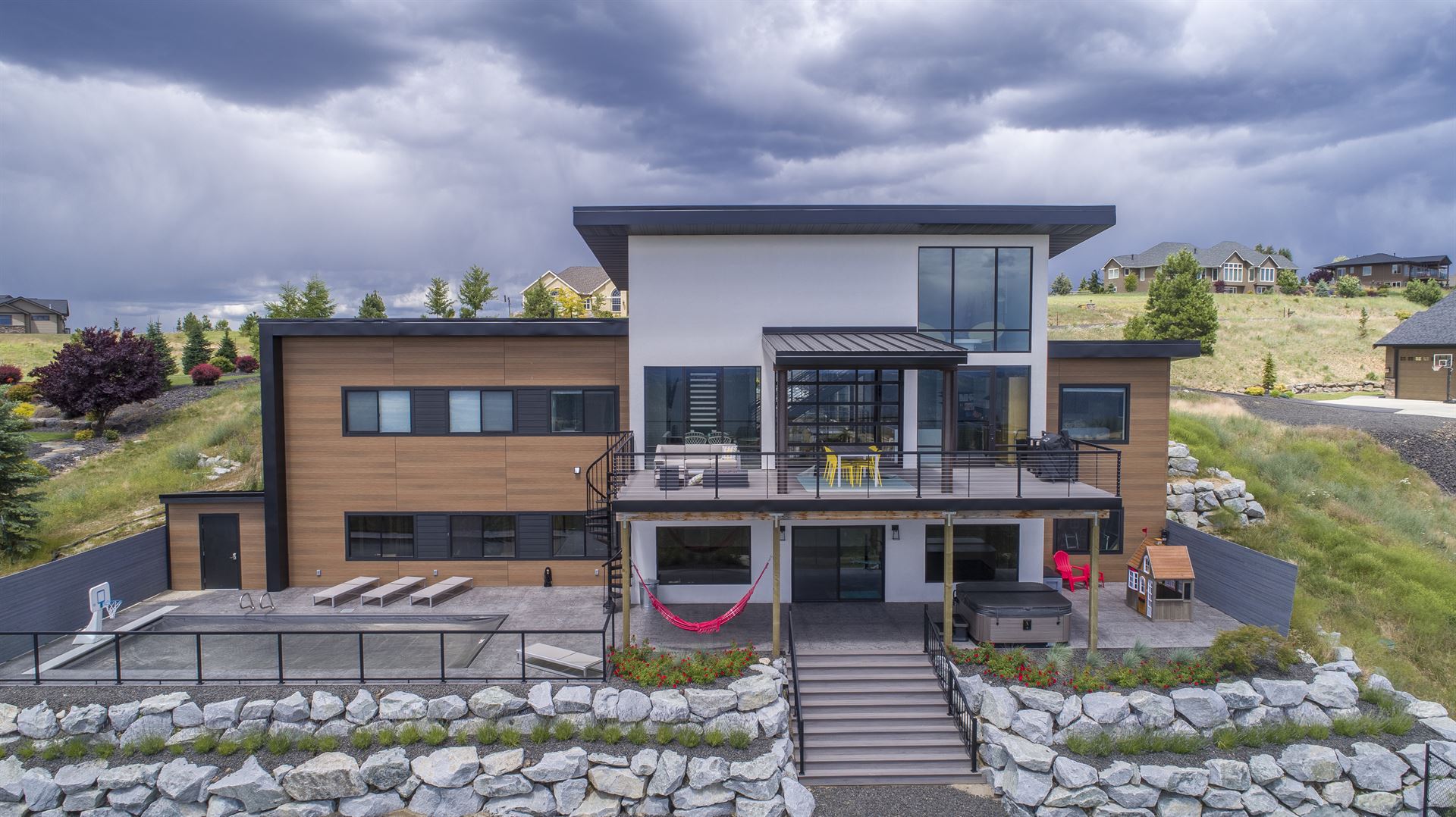 Modern home with plants and rocks incorporated in the landscape and a stormy sky featuring VintageWood Cedar