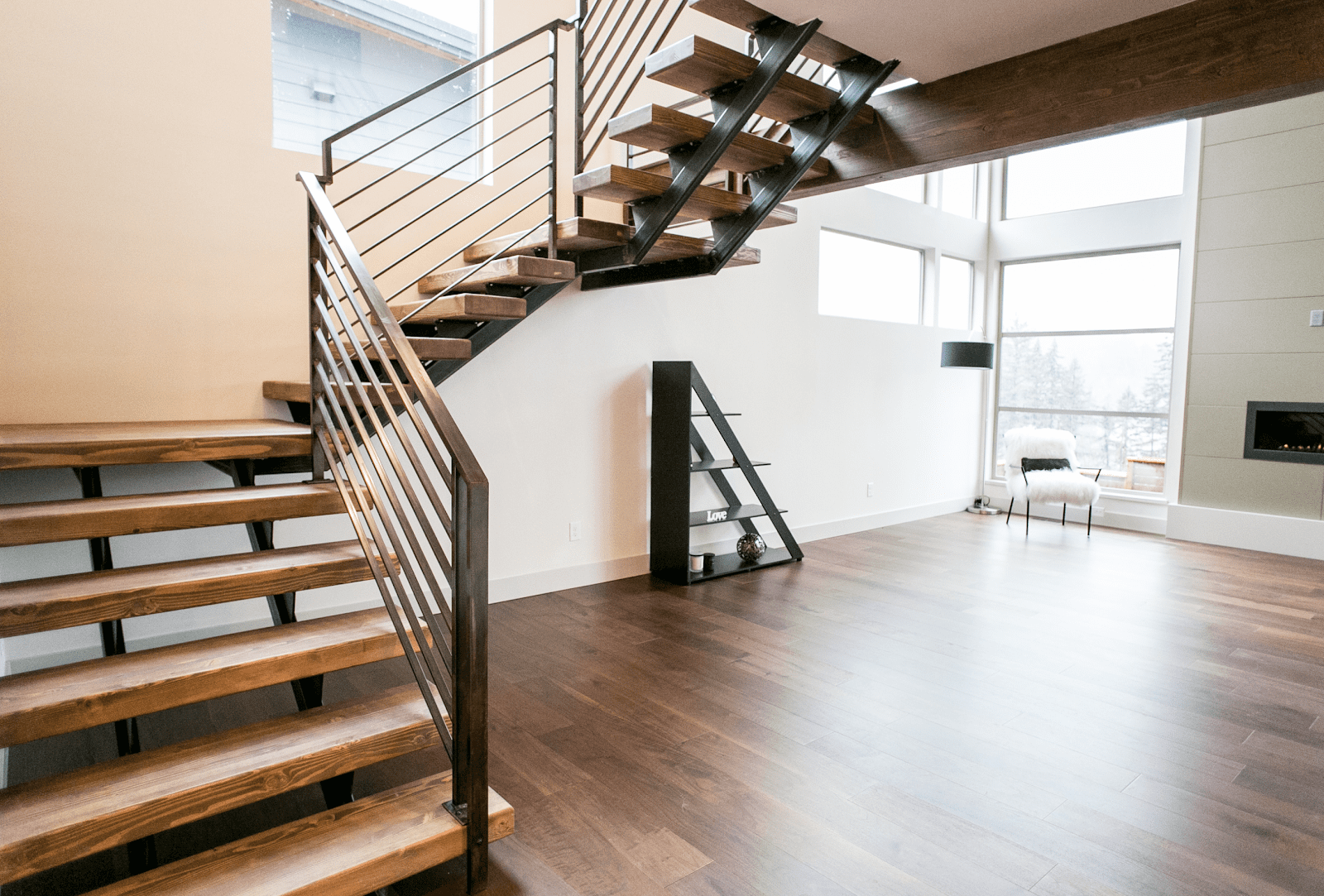 A close-up view of wood stairs with a dark metal railing.