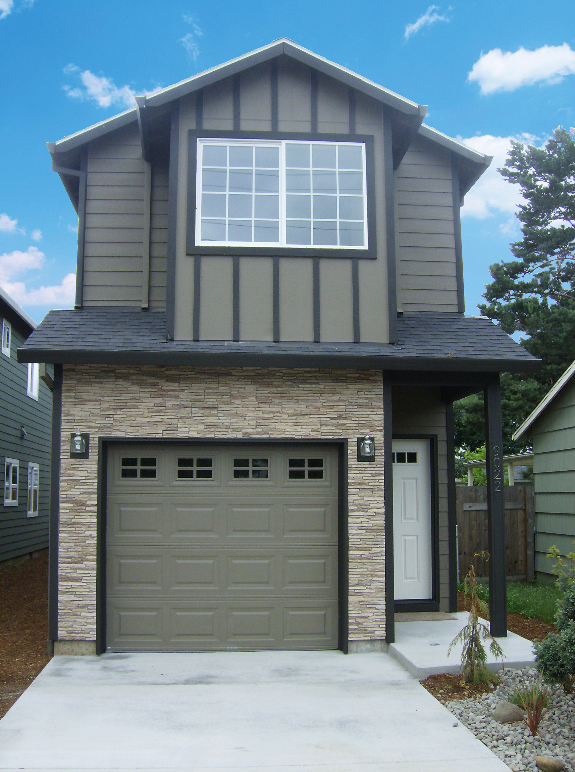 Front elevation of two-story home with multiple siding types, looking at garage door and front door.
