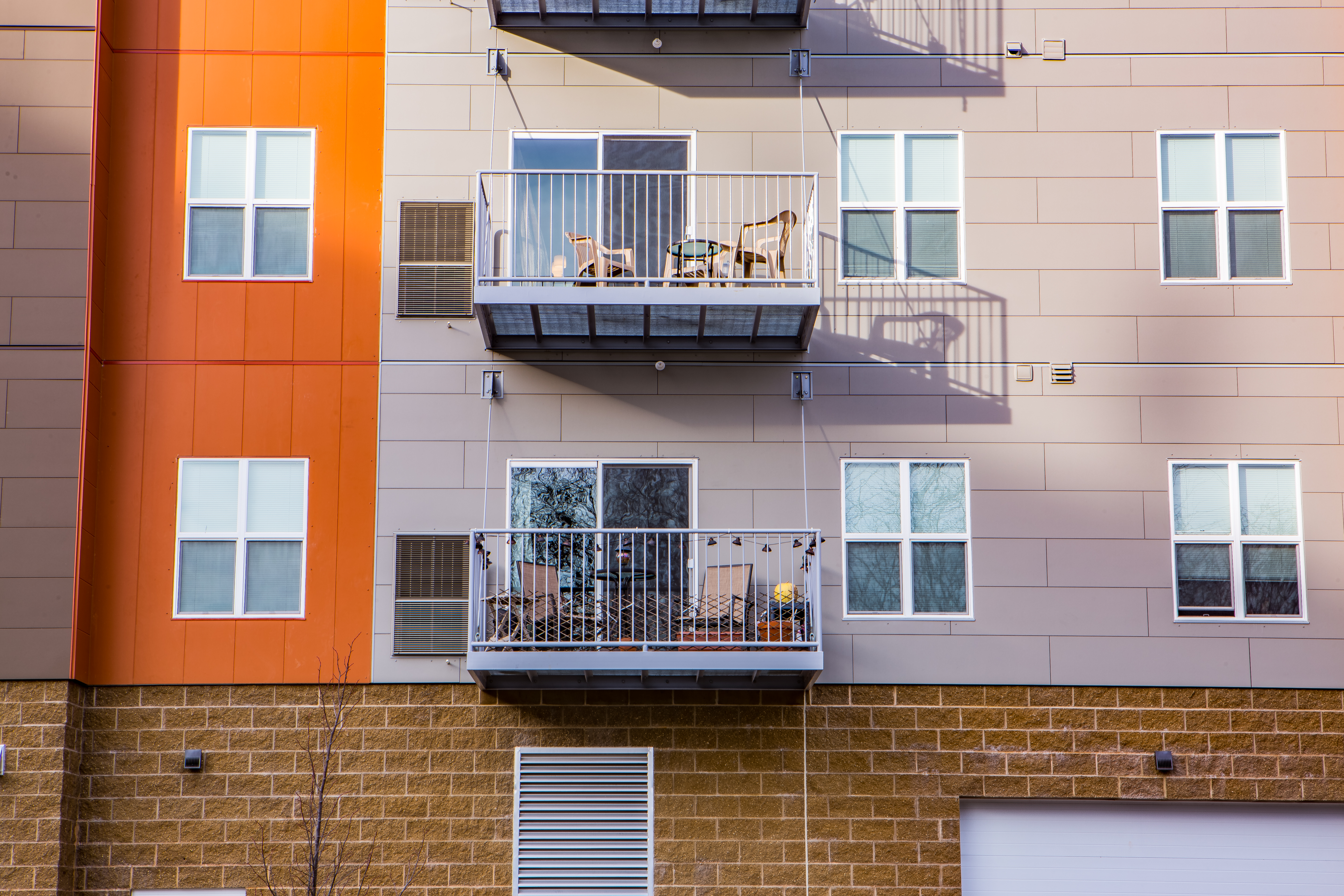 Multi-story student housing with balconies and orange, grey and brick exterior.