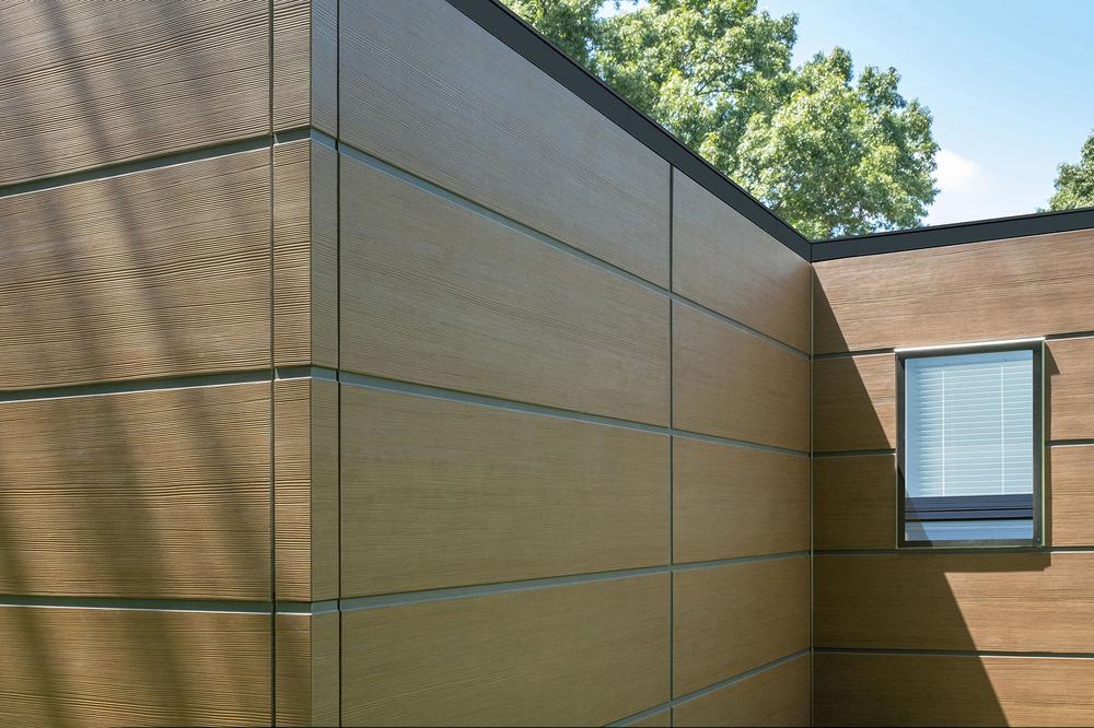 A close-up of Nichiha&rsquo;s RiftSawn fiber cement cladding on a home with trees in the background.