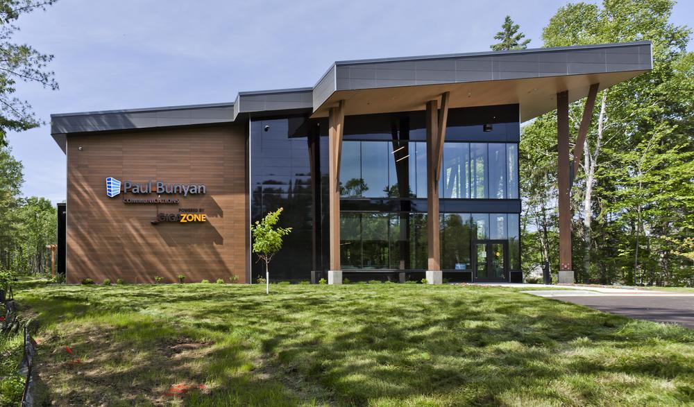 Communications building with large glass windows and green grass and trees