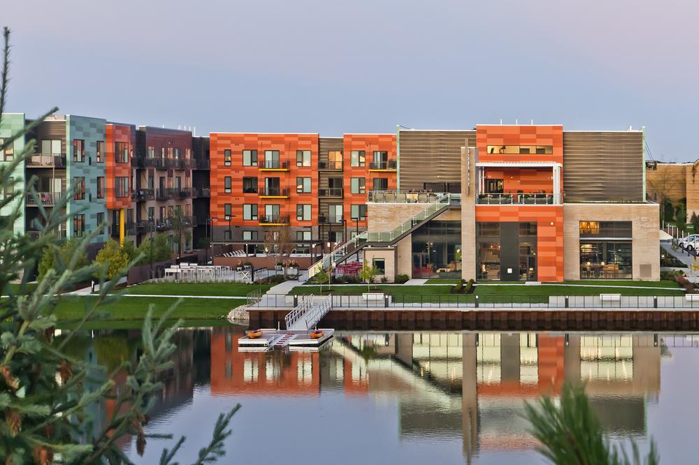 444 Social multifamily building utilizing Nichiha&rsquo;s custom orange fiber cement cladding. It&rsquo;s next to a dock overlooking the water.
