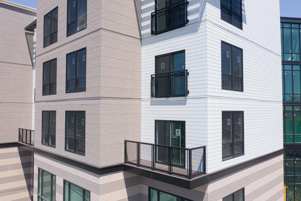 This large complex has white and tan siding. There are a couple of balconies and various rectangular windows on each side of the building.