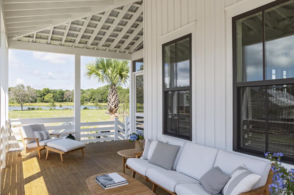 This covered patio area has white and wooden furniture with plants scattered throughout the space.