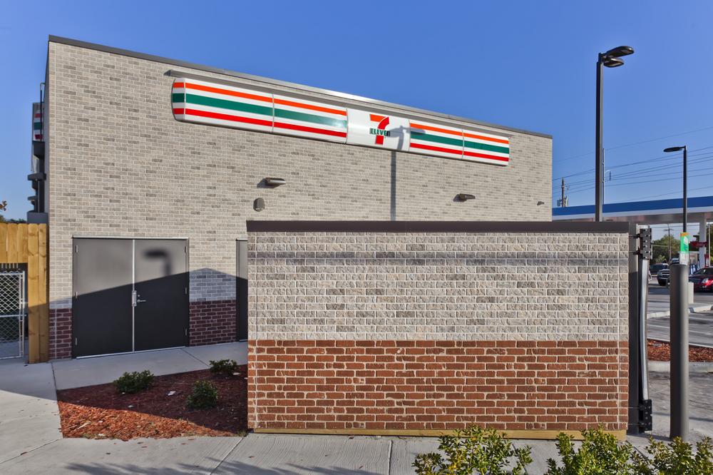 View of 7-Eleven convenience store with detached building and gray and red brick siding.