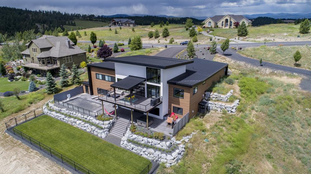 A white, brown and black home with Nichiha fiber cement siding is the center focal point in this photo. There is a cloudy sky, a few neighboring homes and a green lawn surrounding the home.