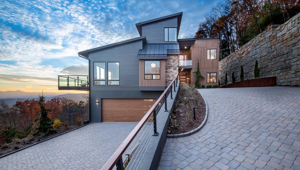 A brown and dark blue home in Nichiha fiber cement siding is the focal point of the photo. There is a balcony looking out into the valley on the front side of the home.