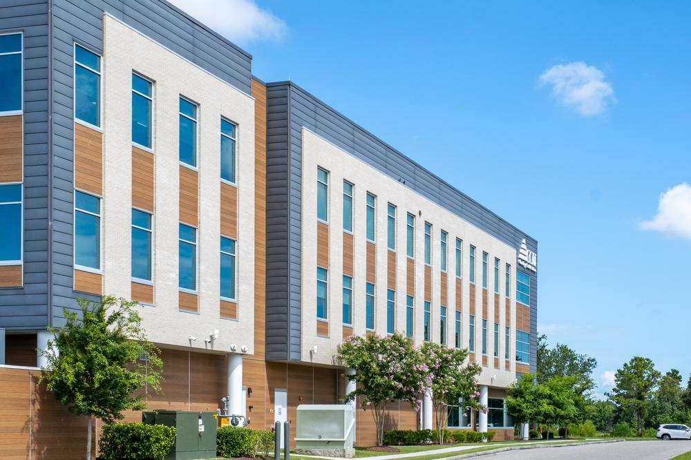 Corning Credit Union is protected with Nichiha’s Vintagewood in blue, tan, and wooden planks. The sky behind the building is blue and there are green trees below it.