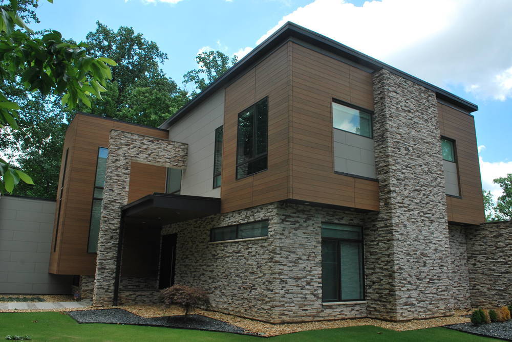 Mixed stone house with cubic features and brown siding.