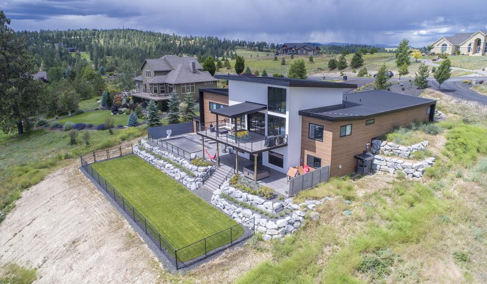 Modern home with white and wood look fiber cement siding built on a hill in mountains.