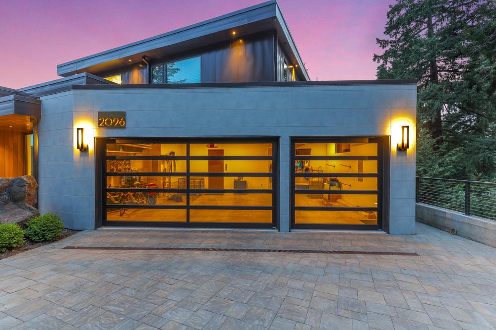 This attached garage has a concrete exterior with light fixtures on each side of the garage doors.