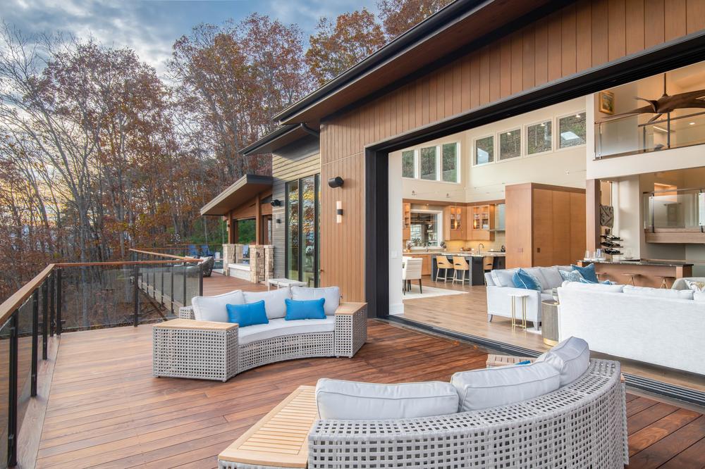 This home has a large deck area that overlooks a scenic view. There are two curved couches on the deck.