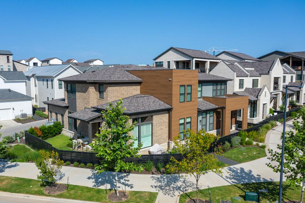 This brick and wood-like modern home stands out in a residential community that has mainly homes with white or light-colored siding.
