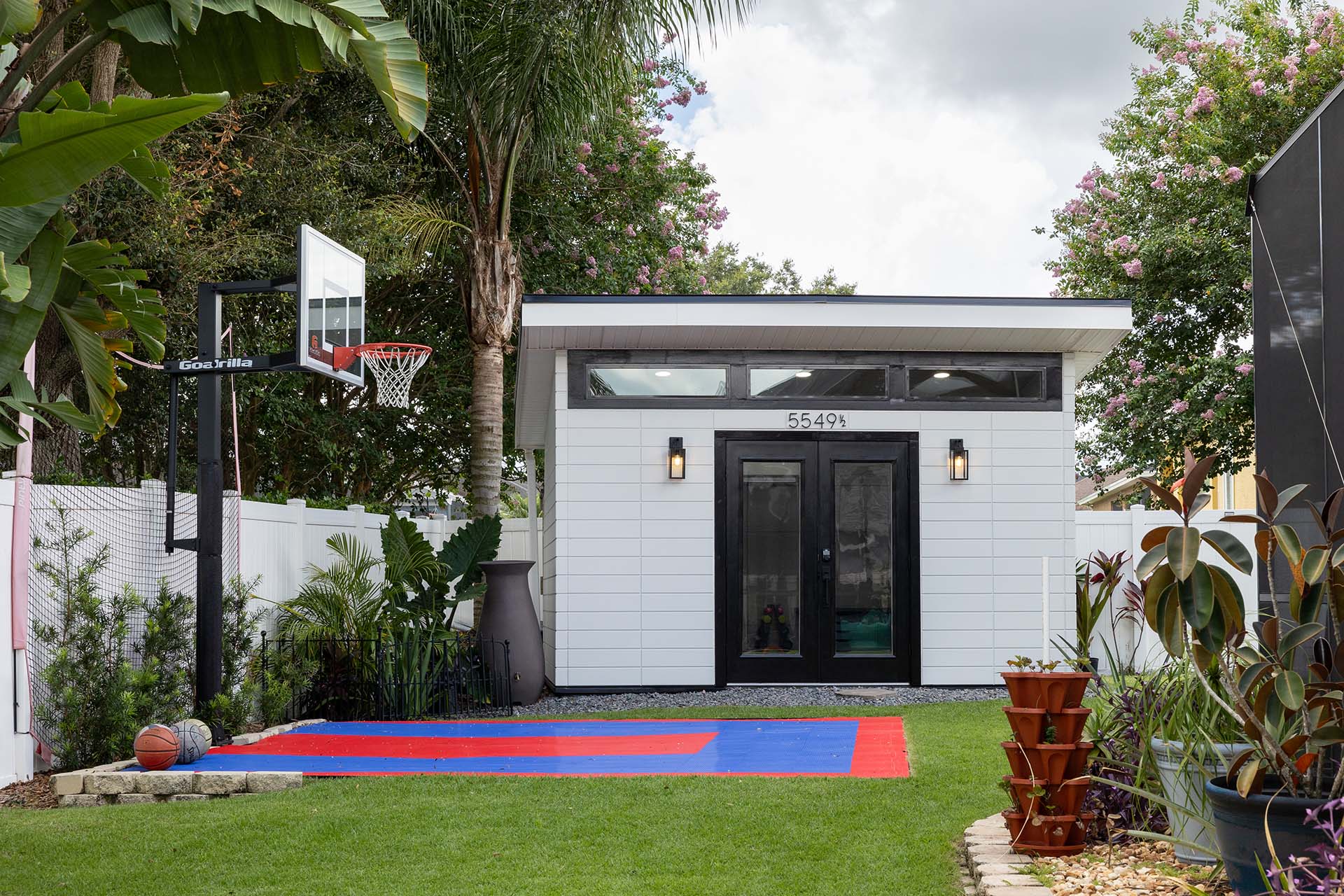 Front view of a small, modern DIY studio with white Novenary panels from Nichiha and a basketball court in front of it